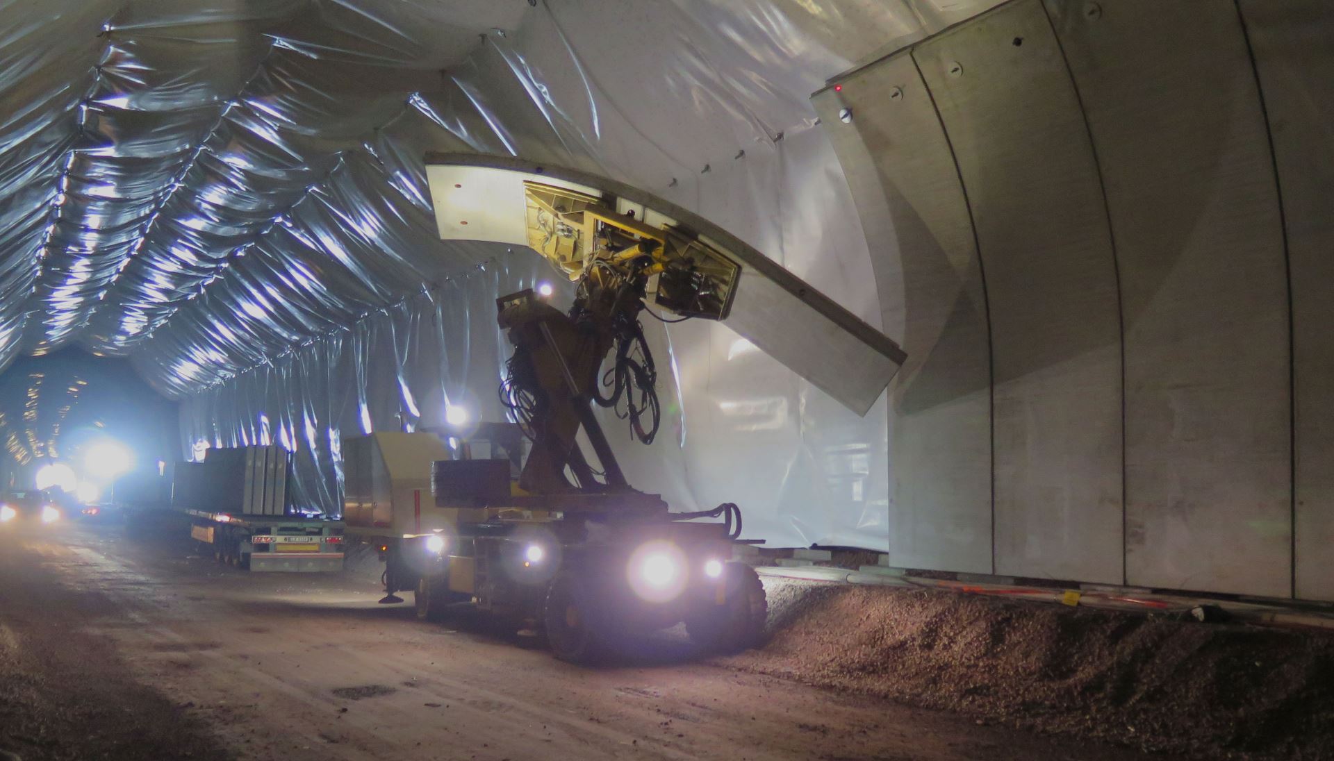 Et betongelement løftes opp for å monteres på fjellbolter i en jernbanetunnel